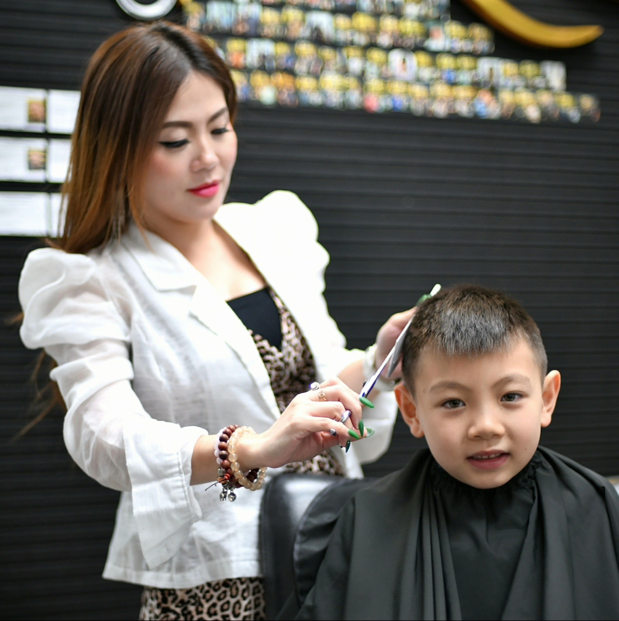 Professional barber Talena precisely cutting a young boy's hair